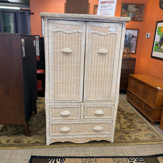 Wicker armoire in a room with orange walls and other furniture.