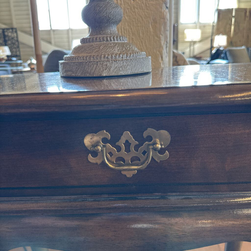 Wooden surface with a decorative lamp and ornate handle.