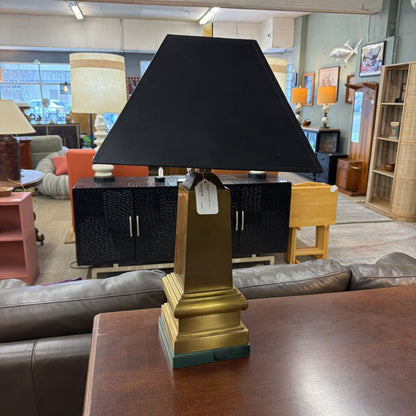 Black lampshade on a gold base in a furniture store setting