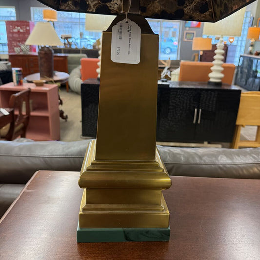 Gold pedestal lamp with a tag on a table in a furniture store setting
