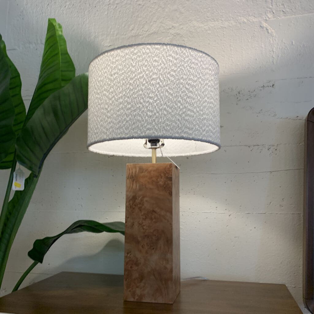 Table lamp with marble base and textured shade next to a plant