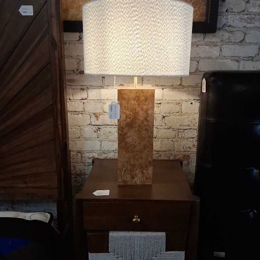 Table lamp with marble base on a wooden nightstand against a brick wall.