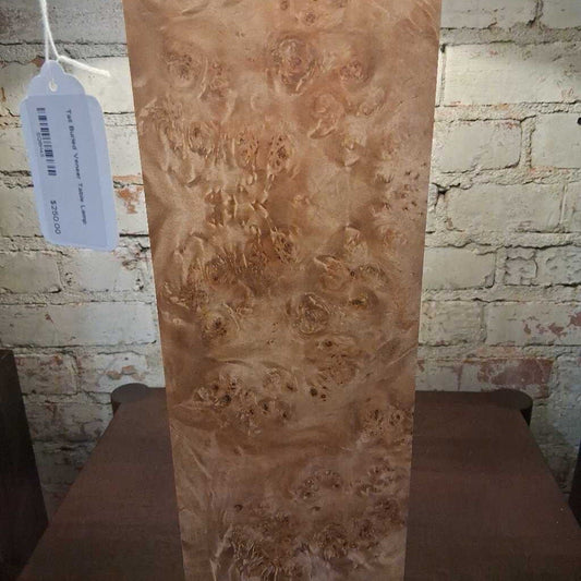 Wooden slab with a burl pattern against a brick wall.