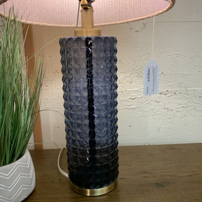 Decorative table lamp with textured blue base and pink lampshade on a wooden surface.
