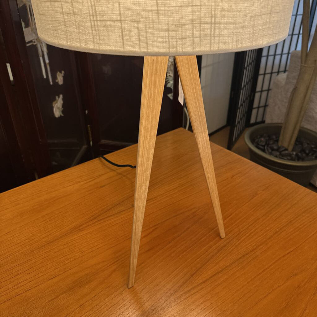 Table lamp with wooden base and beige lampshade on a wooden surface.