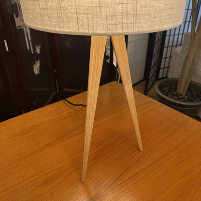 Table lamp with wooden base and beige lampshade on a wooden surface.