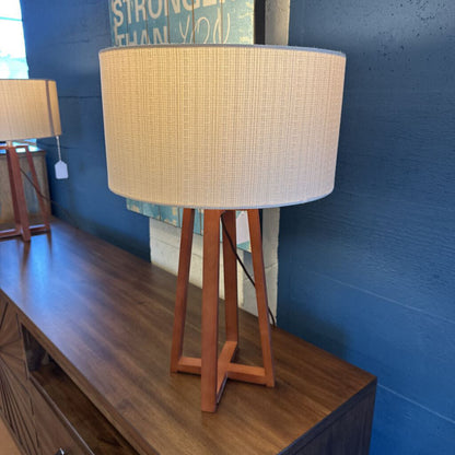 Table lamp with woven shade on a wooden surface against a blue wall