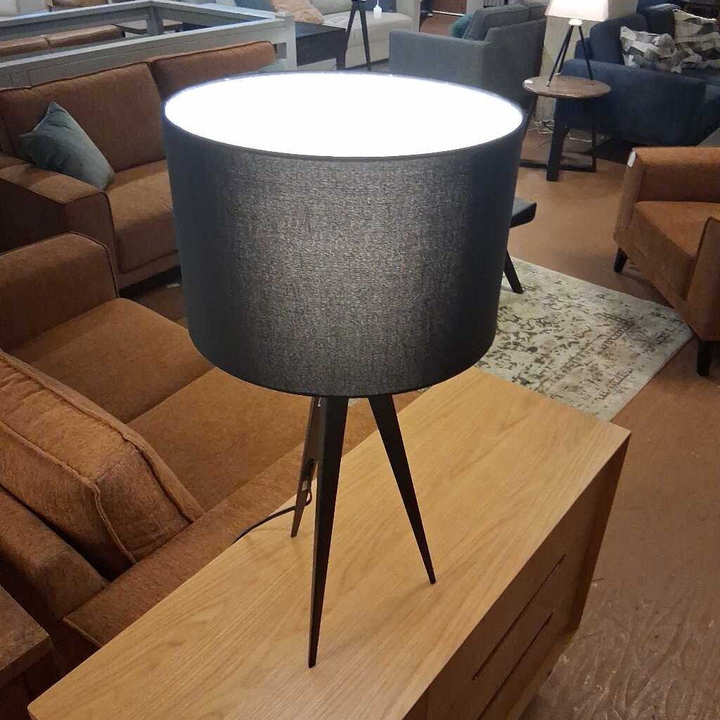 Gray textured lamp on a wooden table with a living room setting in the background
