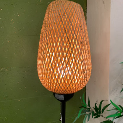 Woven outdoor lamp with a textured design on a green wall.
