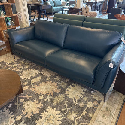 Blue leather sofa in a room with a patterned rug and furniture.