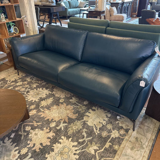 Blue leather sofa in a room with a patterned rug and furniture.