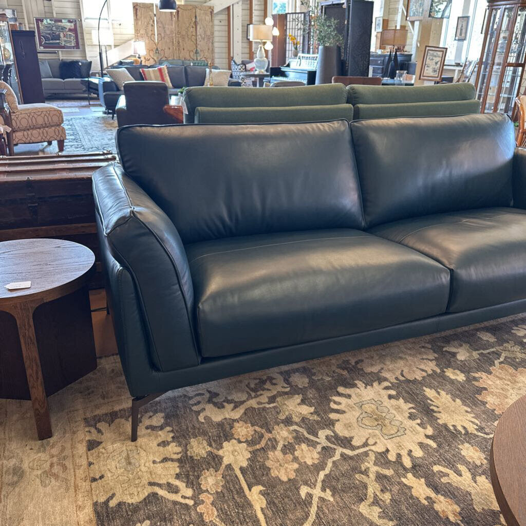 Black leather sofa in a room with patterned rug and furniture.