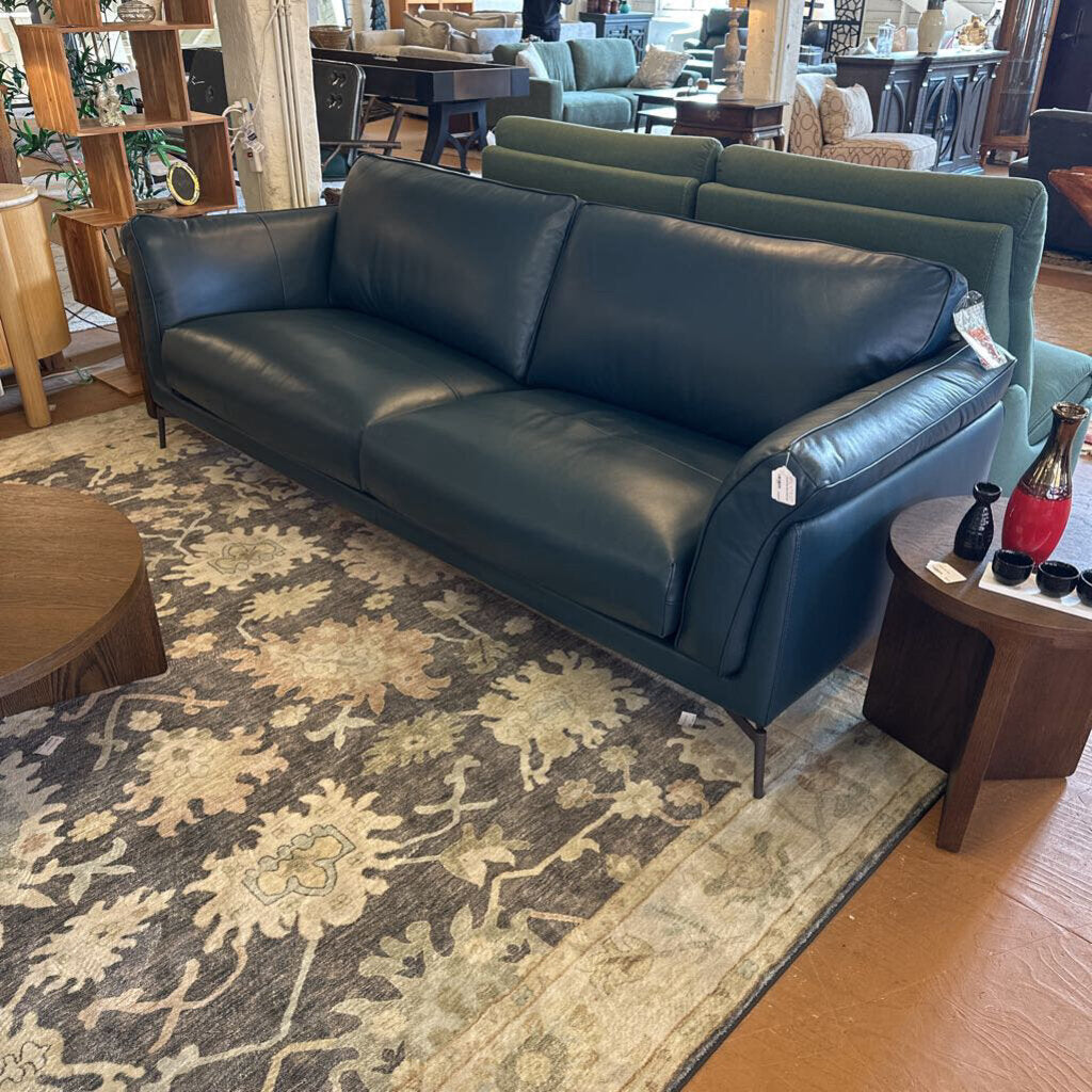Blue leather sofa in a room with a patterned rug and furniture.