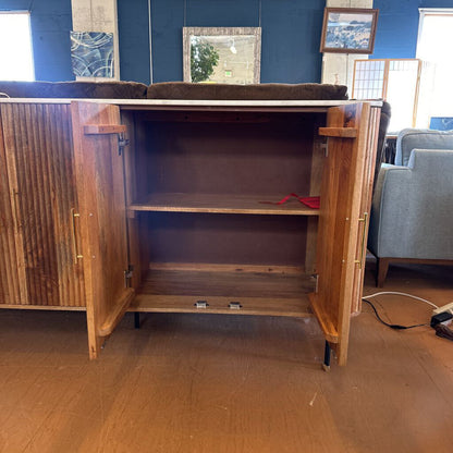 Wooden cabinet with open doors in a room with furniture and decor.