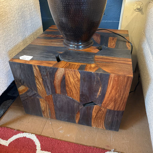 Wooden side table with a textured lamp on top, placed against a neutral background.
