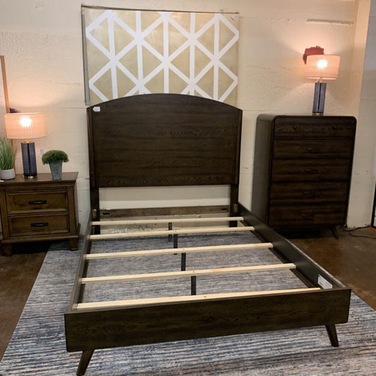 Wooden bed frame in a bedroom setting with nightstands and lamps.