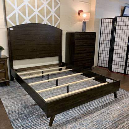 Dark wood bed frame with wooden slats on a blue patterned rug.