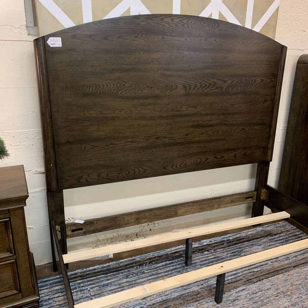 Wooden headboard with decorative carvings on a patterned floor.