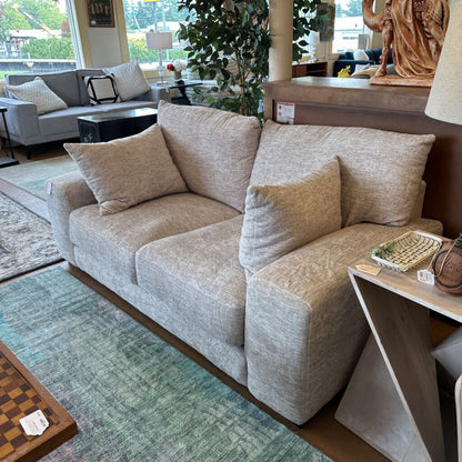 Beige sofa in a living room setting with a rug and decorative items.