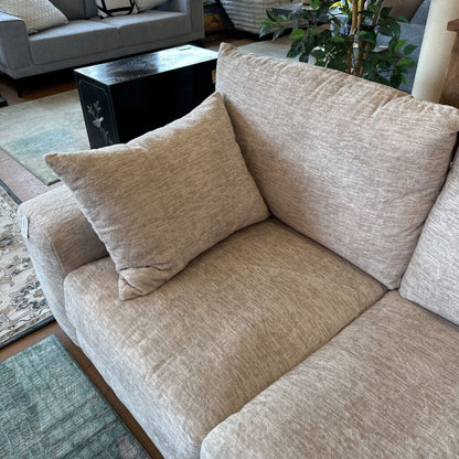 Beige sectional sofa with cushions in a living room setting