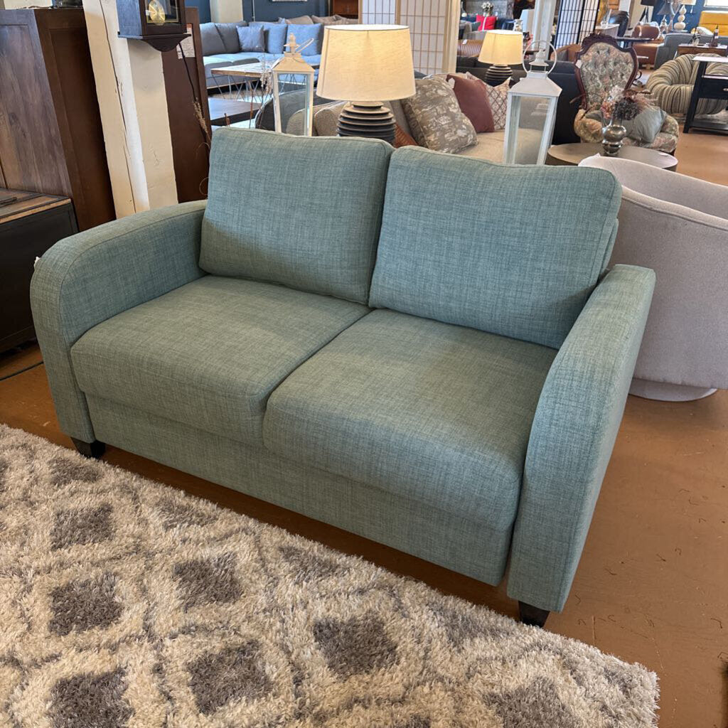 Blue sofa in a furniture store setting with other items in the background