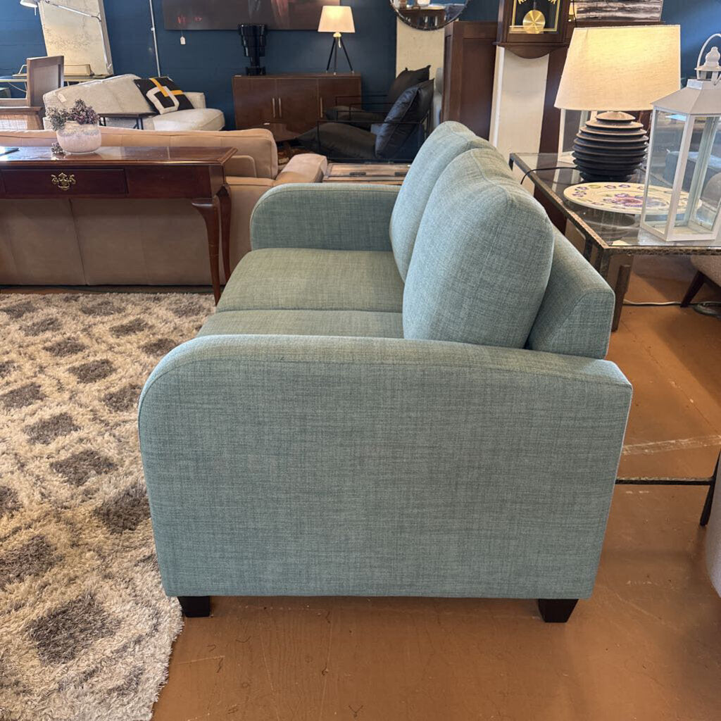 Blue sofa in a showroom setting with other furniture items.