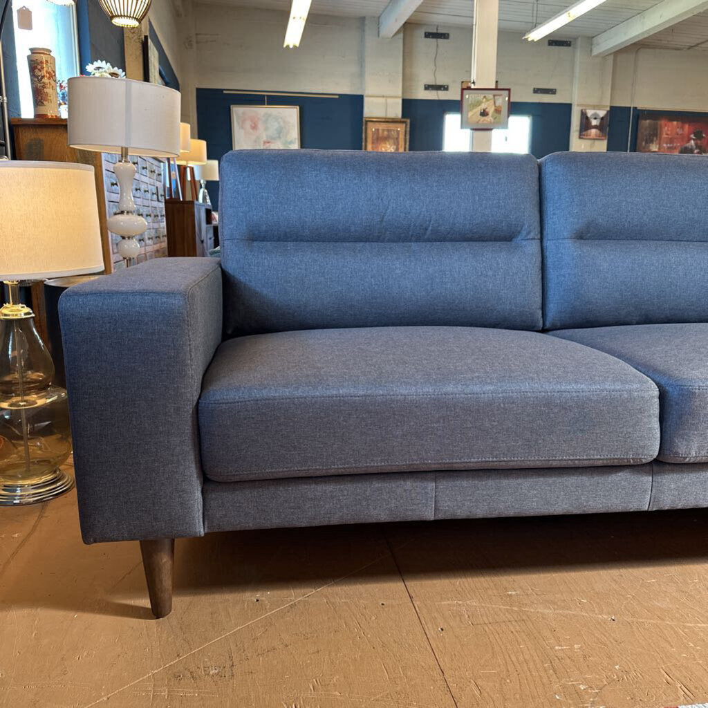 Blue sofa in a store setting with lamps and decor items.