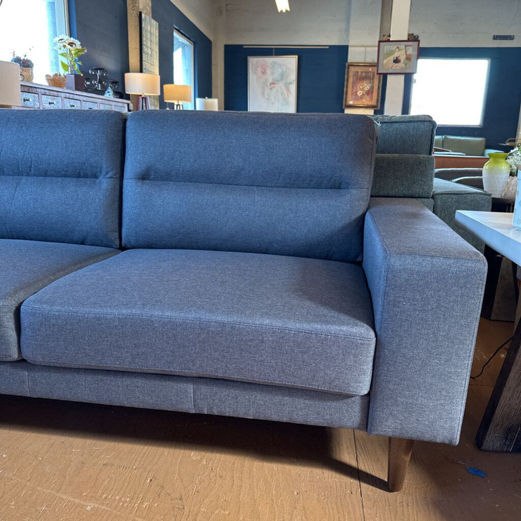 Blue sectional sofa in a living room setting with decor elements.