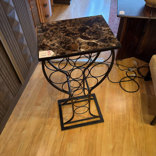 Small table with marble top and decorative metal base on a wooden floor