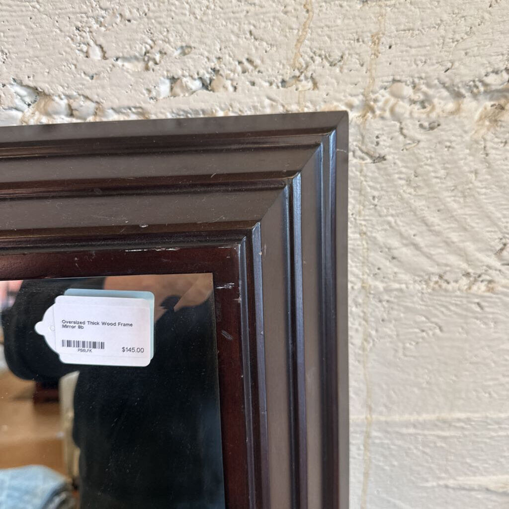 Dark wood picture frame with a price tag on a textured wall.