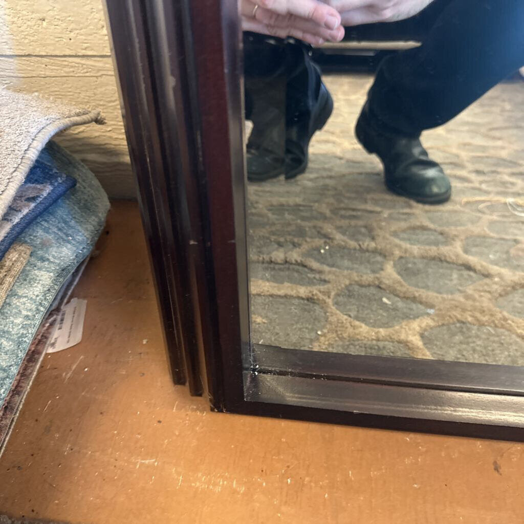 Close-up of a glass door with a person's reflection and a carpeted floor.