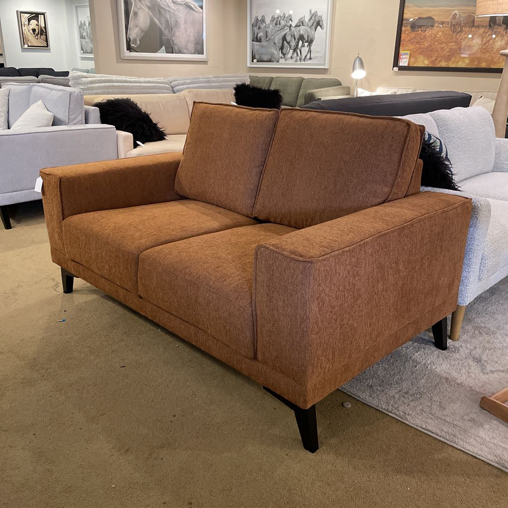 Brown sofa in a room with other furniture and wall art