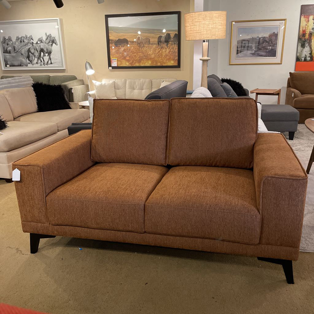 Brown sofa in a showroom with other furniture and decor.