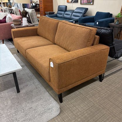 Brown sofa in a furniture store with other sofas and decor items in the background.