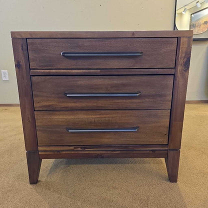Wooden dresser with three drawers on a carpeted floor.