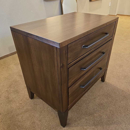 Wooden dresser with three drawers on a carpeted floor