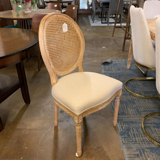 Wooden chair with a wicker backrest and beige cushion in a showroom setting.