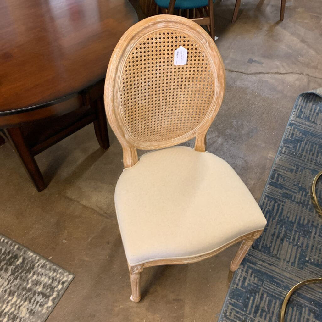Wooden chair with a woven backrest and beige cushion on a floor.