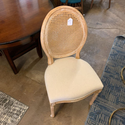 Wooden chair with a woven backrest and beige cushion on a floor.