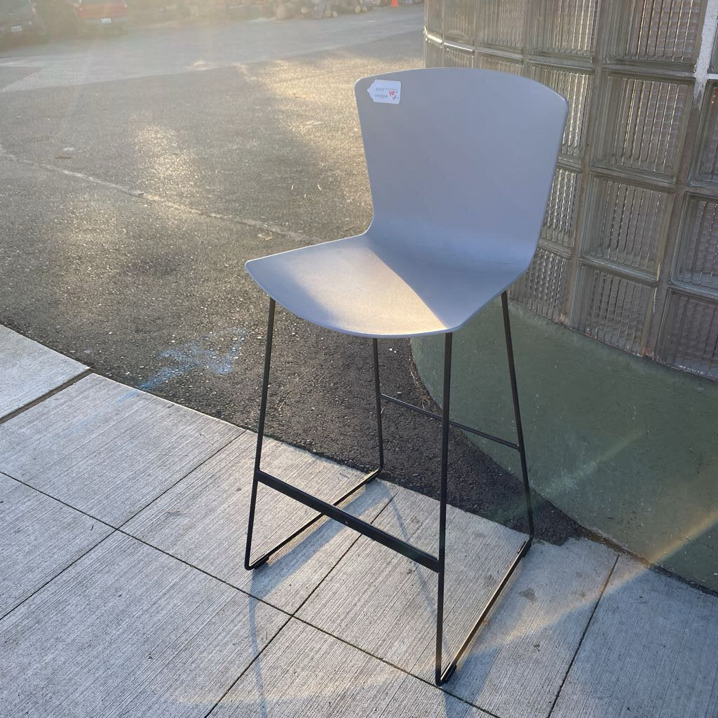 Gray bar stool with black legs on a tiled floor