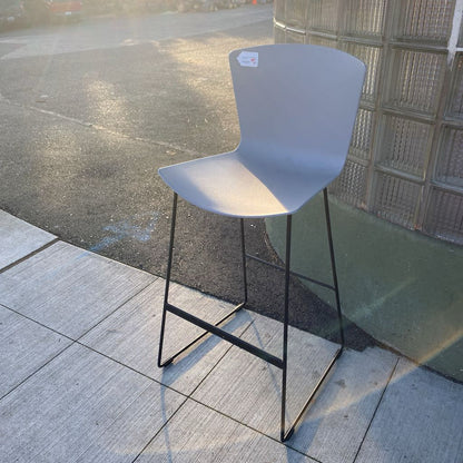 Gray bar stool with black legs on a tiled floor