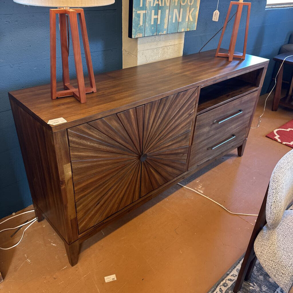 Wooden sideboard with decorative design in a room with a lamp and wall art.