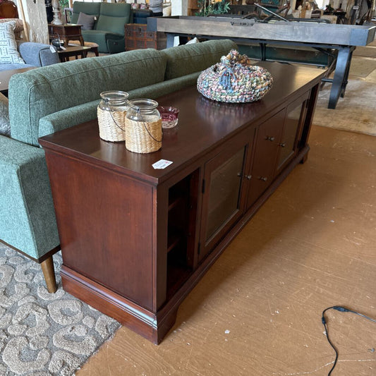Wooden entertainment console with decorative items in a room setting