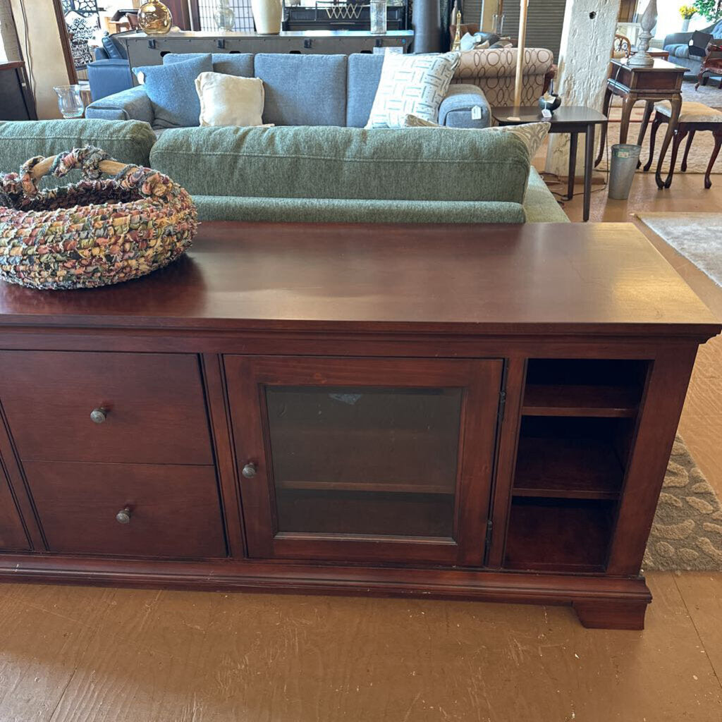 Wooden entertainment console in a living room setting with a couch and coffee table.