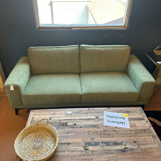 Green sofa in a room with a wooden coffee table and a basket.