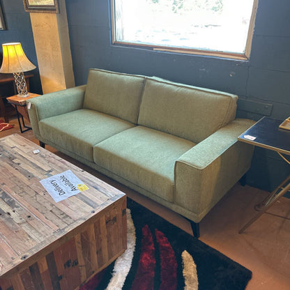 Green sofa in a room with a wooden coffee table and lamp.