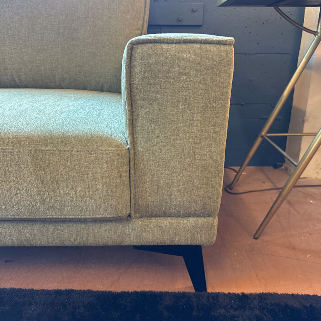 Gray sofa corner with a blue wall and wooden floor in the background