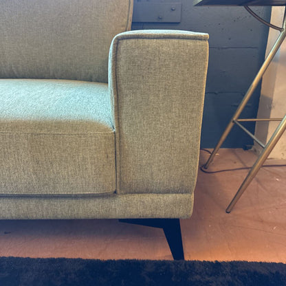 Gray sofa corner with a blue wall and wooden floor in the background