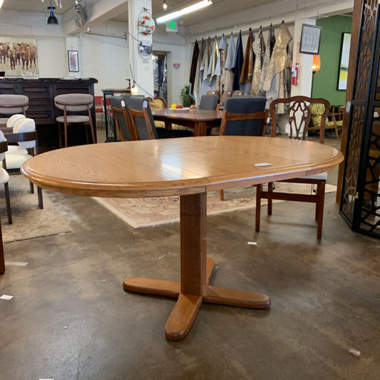 Wooden dining table in a showroom with chairs and other furniture.