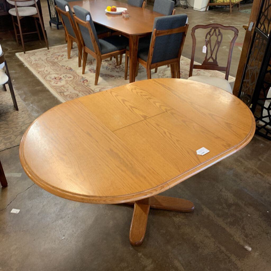 Wooden dining table with a single extension leaf in an indoor setting